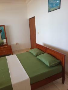 a bedroom with a bed with green sheets at Jasmin Garden in Kalutara