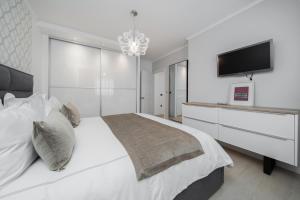 a white bedroom with a large bed and a flat screen tv at Guesthouse Čivljak in Baška Voda