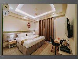 a hotel room with a large bed and a television at Aywa Hotels Edapally in Cochin