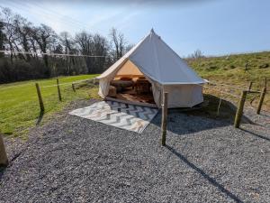 a white tent with a bed in a field at Private Luxury Glamping surrounded by wildlife in Pembrokeshire