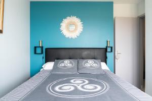 a bedroom with a bed with a blue wall at La Rose des Mers in Tréffiagat