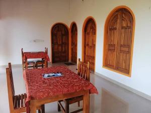 a dining room with a table and four wooden doors at Laxmi Villa in Kalkudah