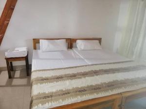 a bed with two pillows and a table in a room at Laxmi Villa in Kalkudah