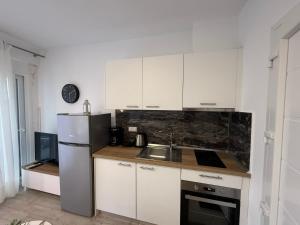 a kitchen with white cabinets and a stainless steel refrigerator at Nefeli's 13,6 Apartment in Orfánion