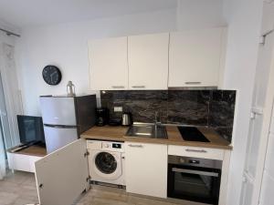 a kitchen with white cabinets and a sink and a refrigerator at Nefeli's 13,6 Apartment in Orfánion +1 photo