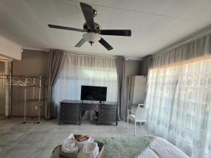 a living room with a ceiling fan and a desk at Grey Crescent living in Welkom