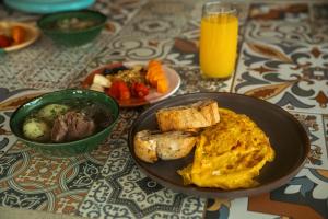 a table with a plate of breakfast food and a bowl of orange juice at Hotel MulataRetreat in La Mesa