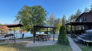 eine Terrasse mit Tischen und Sonnenschirmen neben einem See in der Unterkunft Lejupes in Plānupe