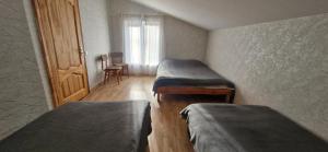 ein Zimmer mit zwei Betten, einem Fenster und einer Tür in der Unterkunft Lejupes in Plānupe