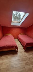 zwei Betten in einem roten Zimmer mit Fenster in der Unterkunft Lejupes in Plānupe + 7 Fotos