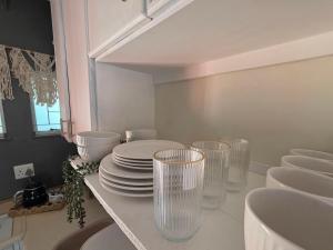 a kitchen with plates and glasses on a counter at Grey Crescent living in Welkom +4 photos