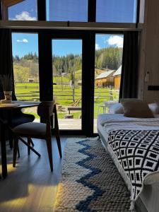 a bedroom with a bed and a table and a view of a field at Osho house Karpaty in Ilʼtsya Dolishna