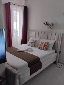 a bedroom with a large white bed with red curtains at Cozy studio at Kisimani Heights Apartment Mombasa in Mombasa +8 photos