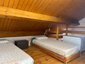 two beds in a room with wooden ceilings at Chalet confort avec cheminée in Camprieu