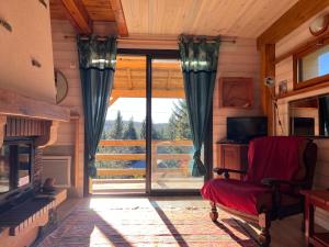 a living room with a fireplace and a red chair at Chalet confort avec cheminée in Camprieu
