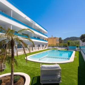 a swimming pool in front of a building with a palm tree at DOLS MAR APARTMENTS in Camp de Mar