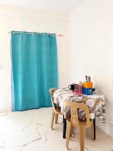 a table with two chairs and a blue shower curtain at Spacious studio 4, AC, kitchenette, central location in Coron