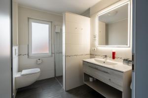 a bathroom with a sink and a toilet and a mirror at Hotel Alter Muschelsaal in Büsum