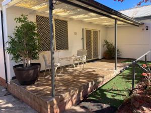 a patio with chairs and a table and a plant at Easy Wagga Stopover, Spacious & Comfortable in Forest Hill