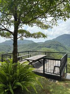 a picnic table and a tree with mountains in the background at Leaf Olu Ella in Yatiyantota