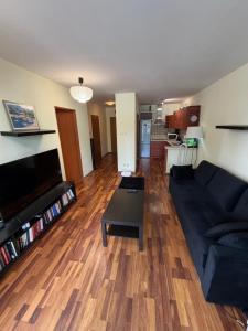 a living room with a black couch and a wooden floor at Elegancki apartament w centrum in Warsaw