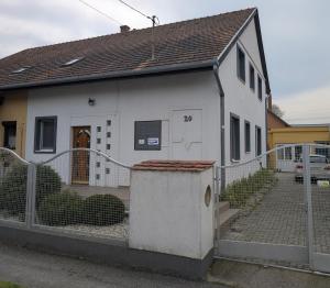 a white house with a fence in front of it at Balaton House in Balatonboglár