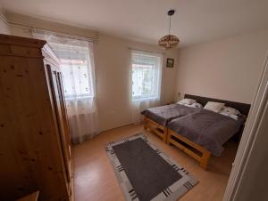 a bedroom with a bed and two windows at Balaton House in Balatonboglár