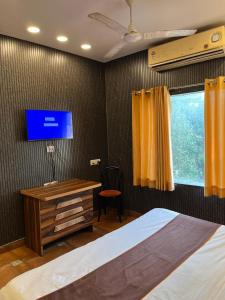 a bedroom with a bed and a desk and a tv at Hotel Mannat Shalimar in New Delhi