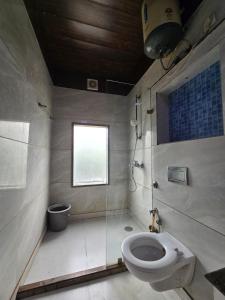 a bathroom with a toilet and a shower and a window at Hotel Mannat Shalimar in New Delhi