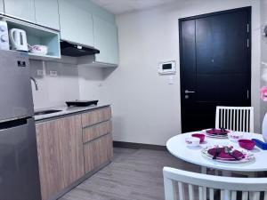 a kitchen with a white table and a black refrigerator at Polished Studio at The Verdin Maple Grove in General Trias