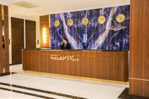 a man standing behind a reception desk in a lobby at Рамада Нукус in Nukus