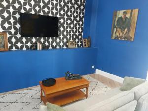 a living room with a couch and a tv on a blue wall at Le Palais Des Marins in Châteauroux +33 photos