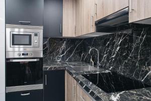 a kitchen with black marble counter tops and a microwave at Apart LA PLANA II in Castellón de la Plana