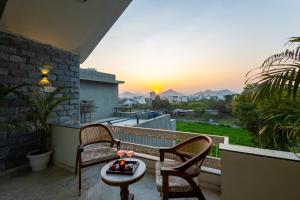 a balcony with two chairs and a table and a sunset at Jolawas Stays Udaipur in Udaipur