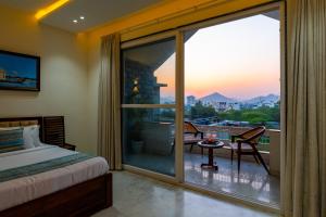 a bedroom with a bed and a balcony with a view at Jolawas Stays Udaipur in Udaipur