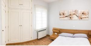 a white bedroom with a bed and a window at Piso de Verano en El Tiemblo in El Tiemblo