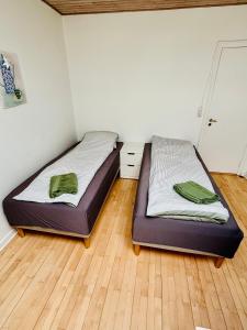 two beds in a room with wooden floors at PRIVATE B&B - EASY ACCESS - 24h SELF CHECK IN-OUT in Odense