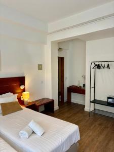 a bedroom with a white bed with two towels on it at Hospedaria Buganvilia Alvor in Alvor