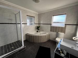 a bathroom with a tub and a shower and a toilet at Wild Thyme in St Helena Bay in West Point +47 photos