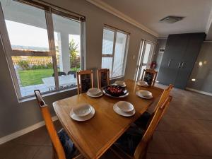 a wooden dining room table with chairs and a large window at Wild Thyme in St Helena Bay in West Point