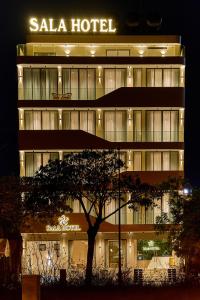 a hotel with a tree in front of it at night at Sala Hotel Phan Thiet in Phan Thiet