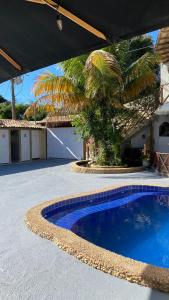 a swimming pool in front of a house with a palm tree at FamilySpace in Búzios