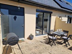 a grill and a table and chairs on a patio at Les G in Gasny