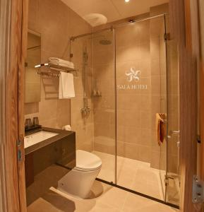 a bathroom with a toilet and a glass shower at Sala Hotel Phan Thiet in Phan Thiet