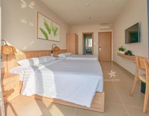 a bedroom with a large bed with white sheets at Sala Hotel Phan Thiet in Phan Thiet