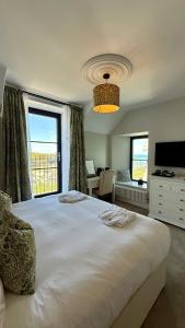 a bedroom with a large white bed with a large window at The Edge Of The Beach in Bude