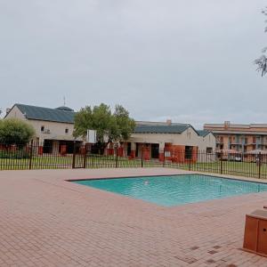 a swimming pool in front of a fence at Cozy Comfortable Apartment with pool in Pretoria