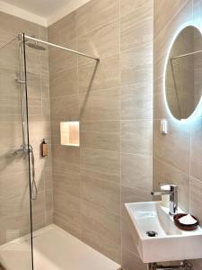 a bathroom with a shower and a sink and a mirror at Hospedaria Buganvilia Alvor in Alvor