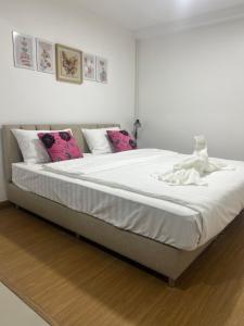 a large white bed with a doll sitting on it at TUK&TOON House in Sathani Ban Thap Chang
