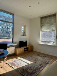 a living room with a television and a rug at Het Kantoor in Philippine
